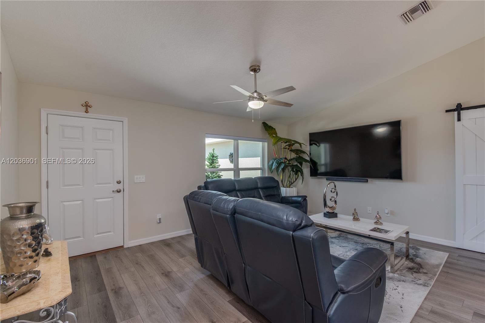 A living room features dark leather reclining sofas, a wall-mounted television, and wood-look flooring — 16365 SW 47 Terrace, Ocala FL 34473, OCALA, FL