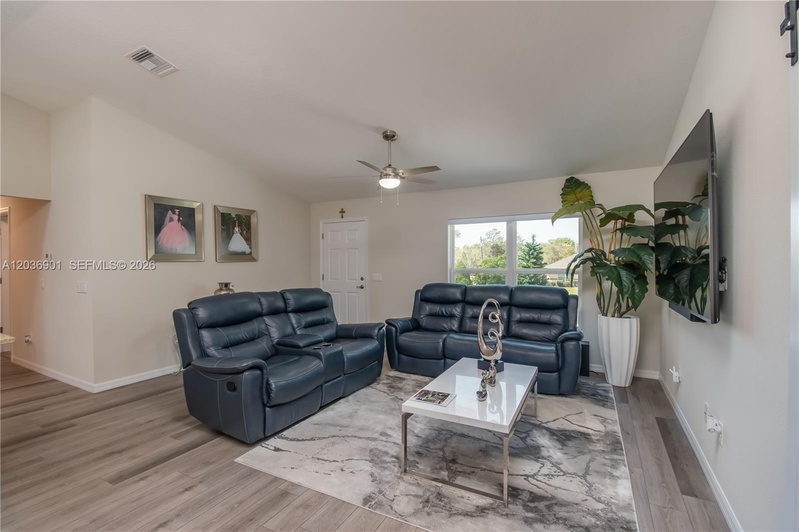 A living room features two blue leather sofas, a white coffee table, and a television — 16365 SW 47 Terrace, Ocala FL 34473, OCALA, FL