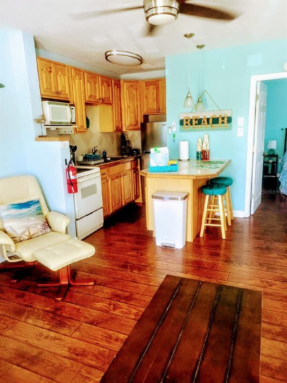 A kitchen with light wood cabinets, a breakfast bar, and a beige armchair — 13343 GULF BOULEVARD UNIT C-12, MADEIRA BEACH, FL