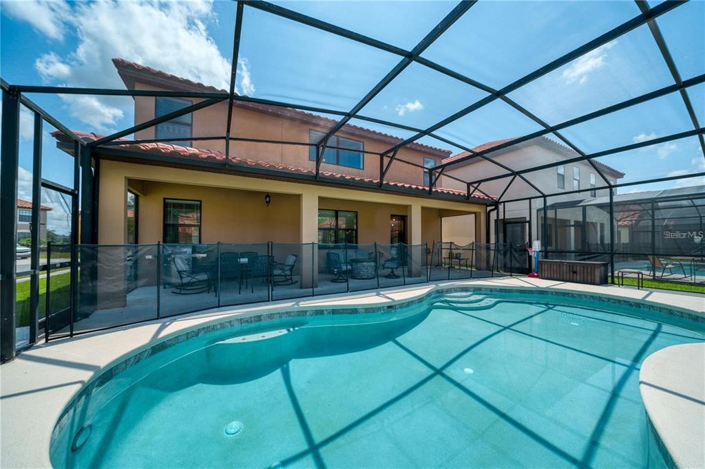 A swimming pool with a screened-in lanai and a covered patio area behind a house — 2641 TRANQUILITY WAY, KISSIMMEE, FL
