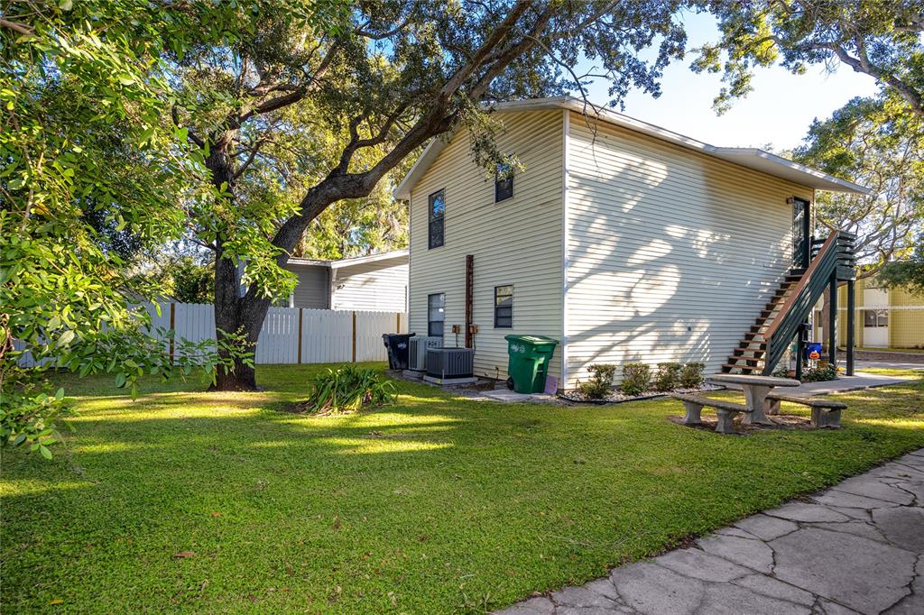 A two-story house with light yellow siding, an exterior staircase, and a grassy backyard — 1303 S MOODY AVENUE, TAMPA, FL