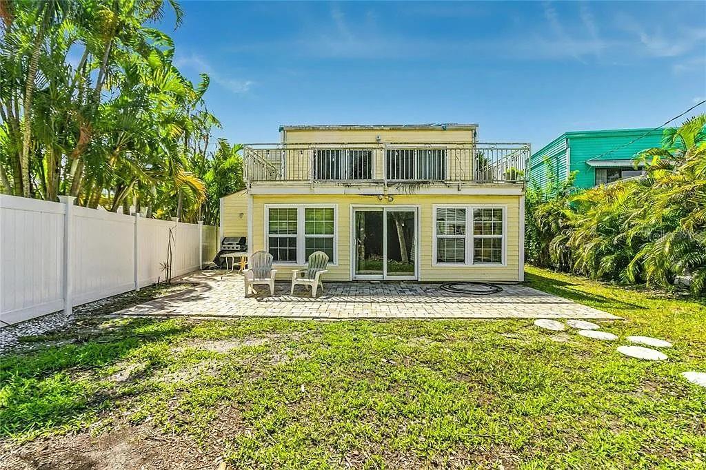 A two-story yellow house features a back patio, a second-floor balcony, and palm trees — 643 CALLE DE PERU, SARASOTA, FL