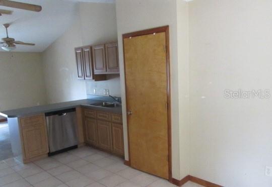 A kitchen features light wood cabinets, a stainless steel dishwasher, and a tall pantry door — 824 BERRYHILL CIRCLE, FRUITLAND PARK, FL
