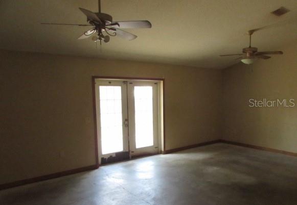 An interior room with concrete floors, two ceiling fans, and a set of French doors — 824 BERRYHILL CIRCLE, FRUITLAND PARK, FL