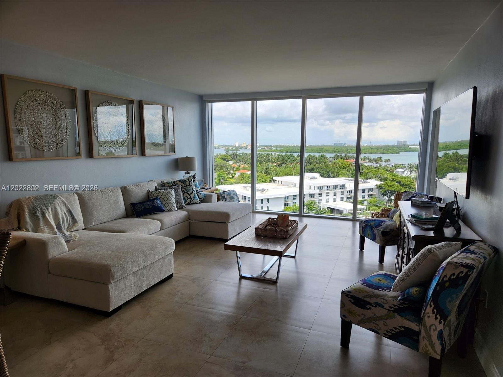 A living room features a sectional sofa, patterned armchairs, and floor-to-ceiling windows overlooking water — 10275 Collins Ave # 824, Bal Harbour FL 33154, BAL HARBOUR, FL