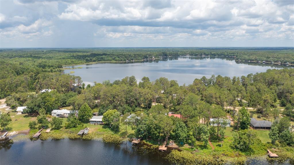 An aerial view shows several houses nestled along a tree-lined lake with private docks — 303 RILEY LAKE DRIVE, HAWTHORNE, FL