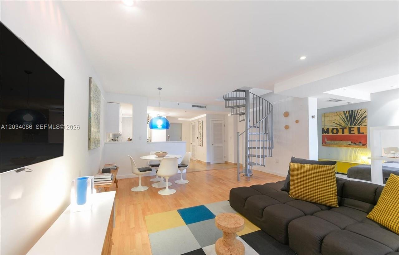 A living room features a spiral staircase, a dining area, and a dark sectional sofa — 3339 Virginia St # 22, Miami FL 33133, MIAMI, FL