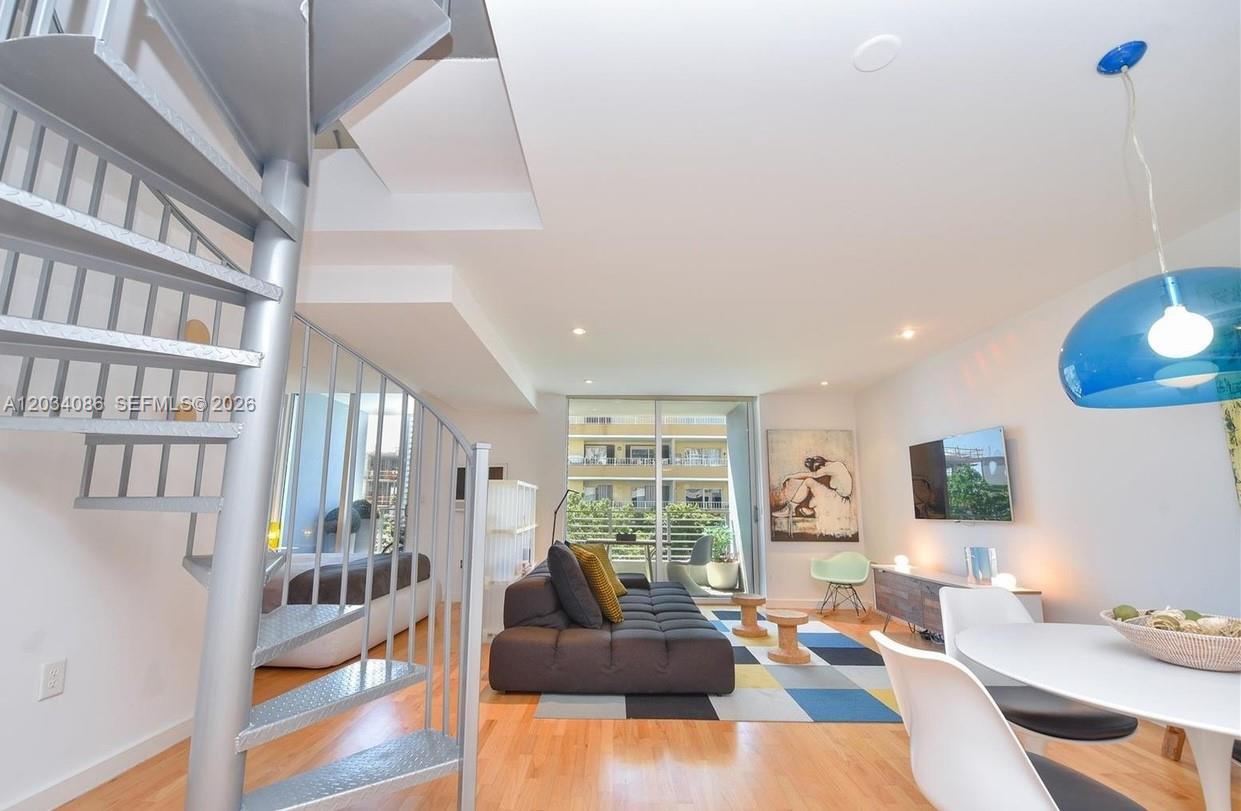 A living room features a spiral staircase, hardwood floors, and a balcony with outdoor views — 3339 Virginia St # 22, Miami FL 33133, MIAMI, FL