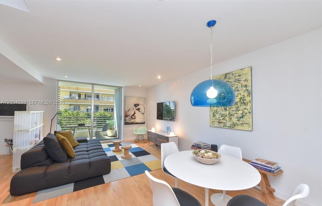 A living and dining area features a dark sofa, a round table, and a balcony — 3339 Virginia St # 22, Miami FL 33133, MIAMI, FL