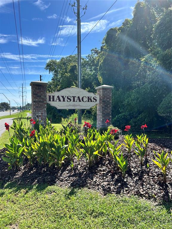 A brick entrance sign for Haystacks sits behind a garden bed with red flowers — 4543 SW 44TH LANE, GAINESVILLE, FL