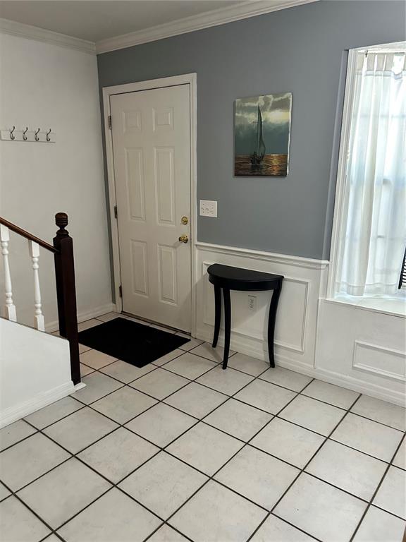 An entryway features white tile flooring, a white door, a half-moon console table, and wainscoting — 4543 SW 44TH LANE, GAINESVILLE, FL