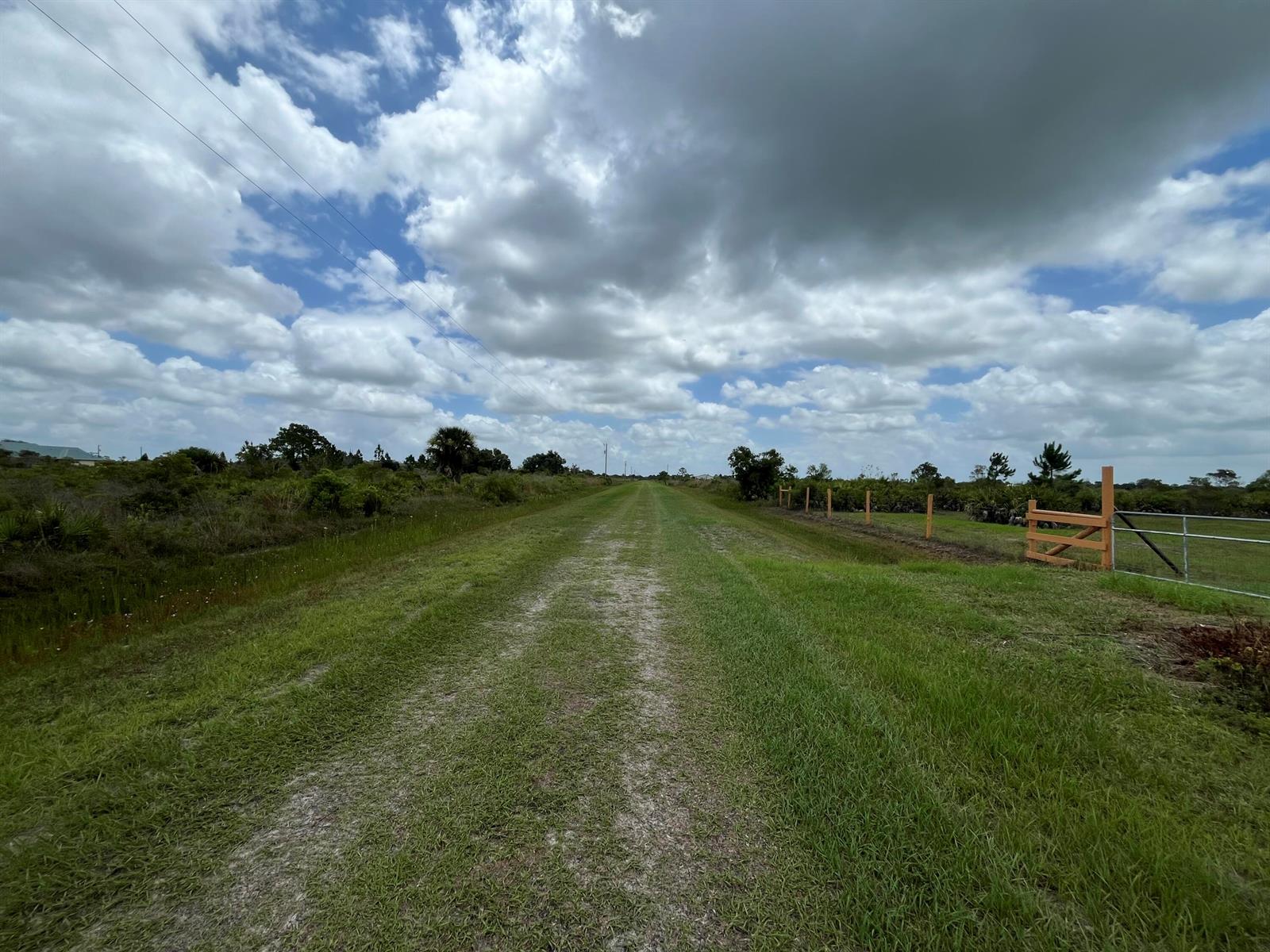 A grassy path leads through a rural landscape with a wooden fence and gate — 19092 NW 250th Street, Okeechobee FL 34972, OKEECHOBEE, FL