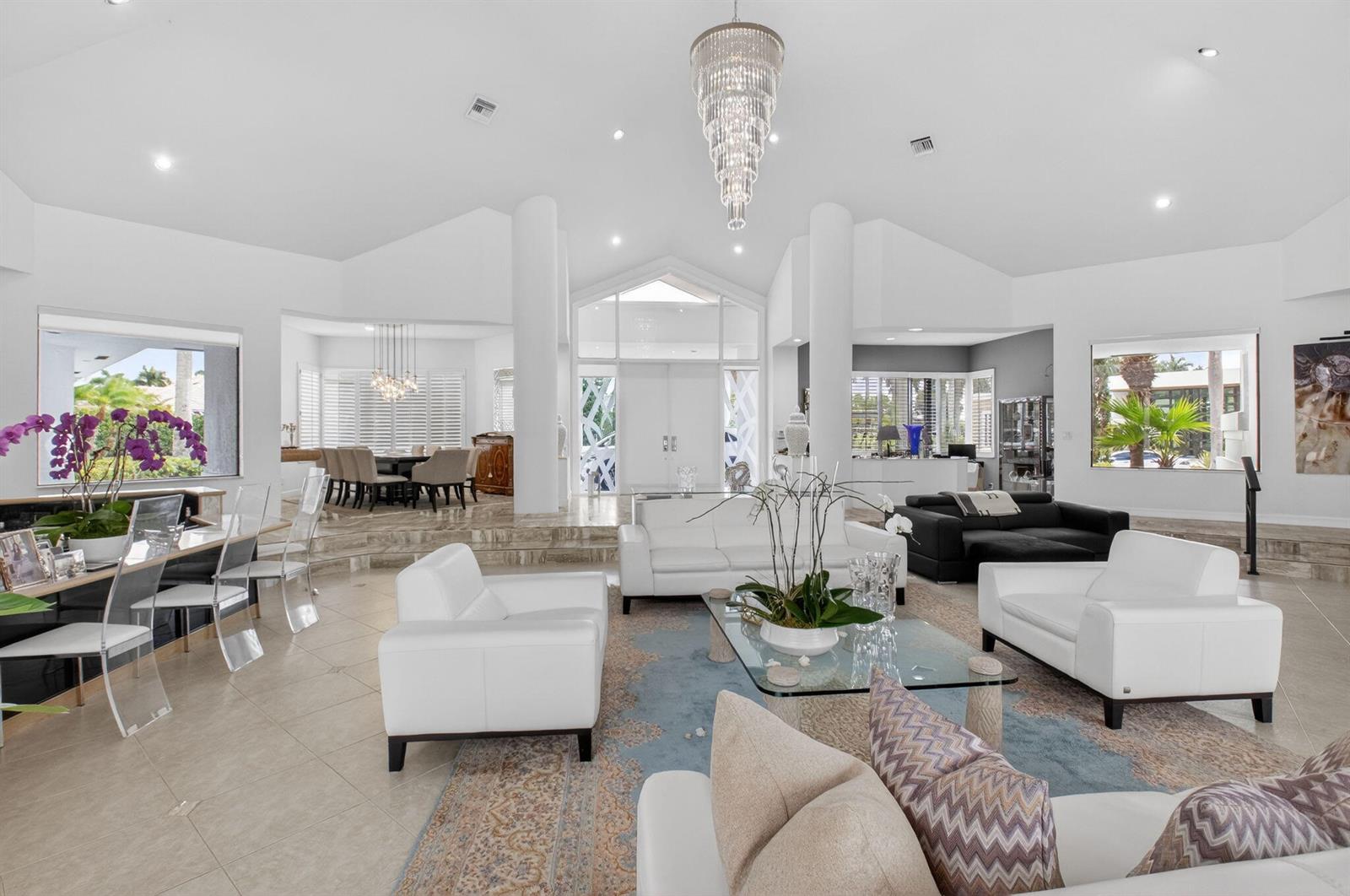 A spacious, open-concept living and dining area features white furniture, marble floors, and a chandelier — 7215 Ballantrae Court, Boca Raton FL 33496, BOCA RATON, FL