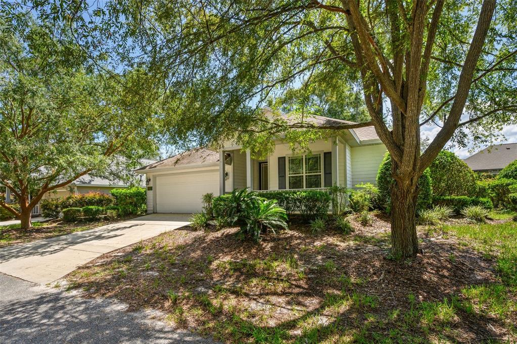 A single-story house with a white garage and siding is surrounded by large shade trees — 7652 SW 85TH DRIVE, GAINESVILLE, FL
