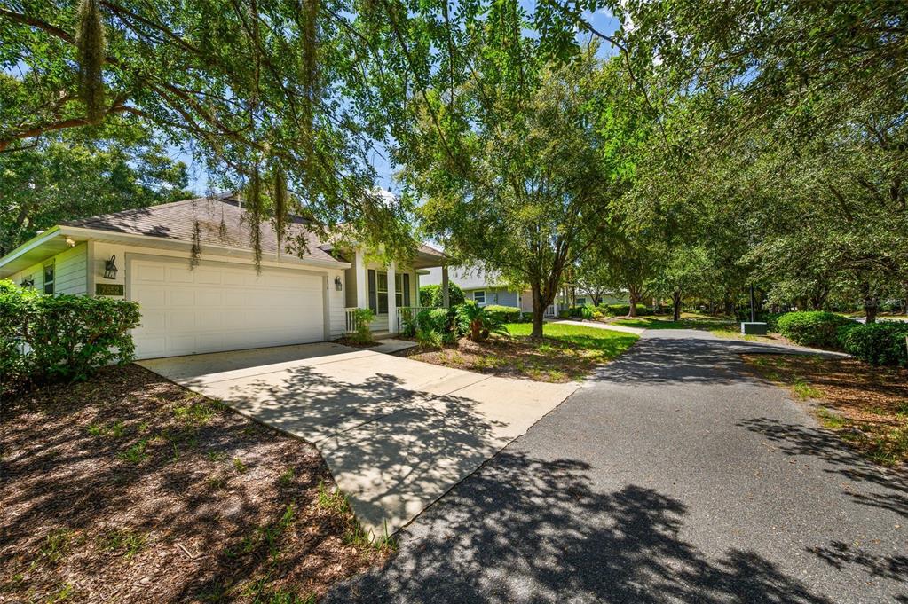 A single-story house with a white garage, concrete driveway, and surrounding trees on a sunny day — 7652 SW 85TH DRIVE, GAINESVILLE, FL