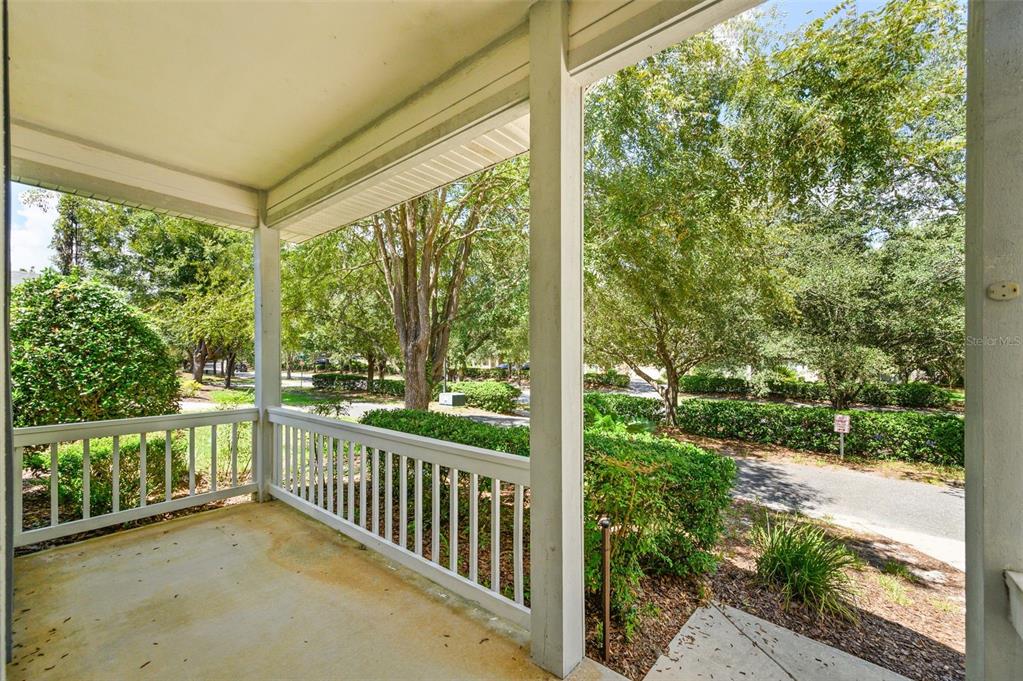A covered porch with a white railing overlooks a paved driveway and surrounding trees — 7652 SW 85TH DRIVE, GAINESVILLE, FL