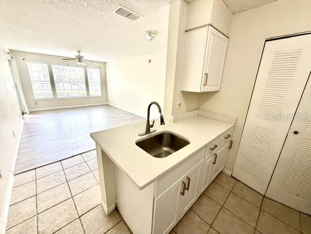 A kitchen island with a stainless steel sink sits before a living area with wood flooring — 1073 S HIAWASSEE ROAD UNIT 1015, ORLANDO, FL