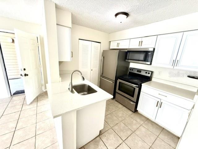 A kitchen features white cabinets, stainless steel appliances, a center island, and tiled flooring — 1073 S HIAWASSEE ROAD UNIT 1015, ORLANDO, FL