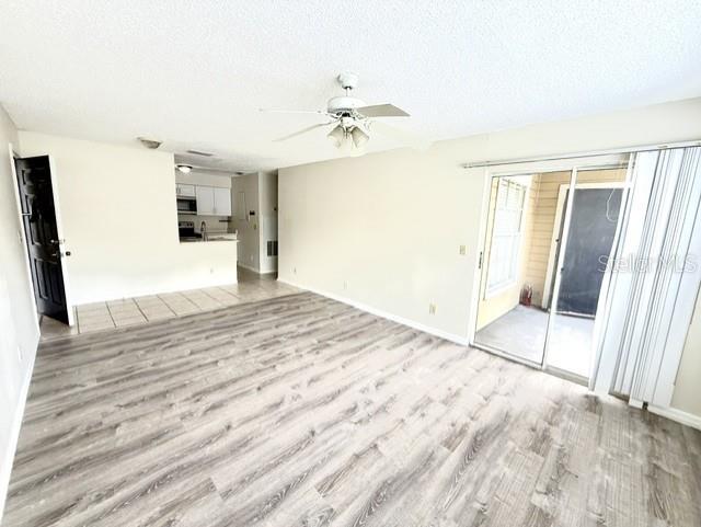 A living room with wood-look flooring, a ceiling fan, and sliding glass doors to a patio — 1073 S HIAWASSEE ROAD UNIT 1015, ORLANDO, FL