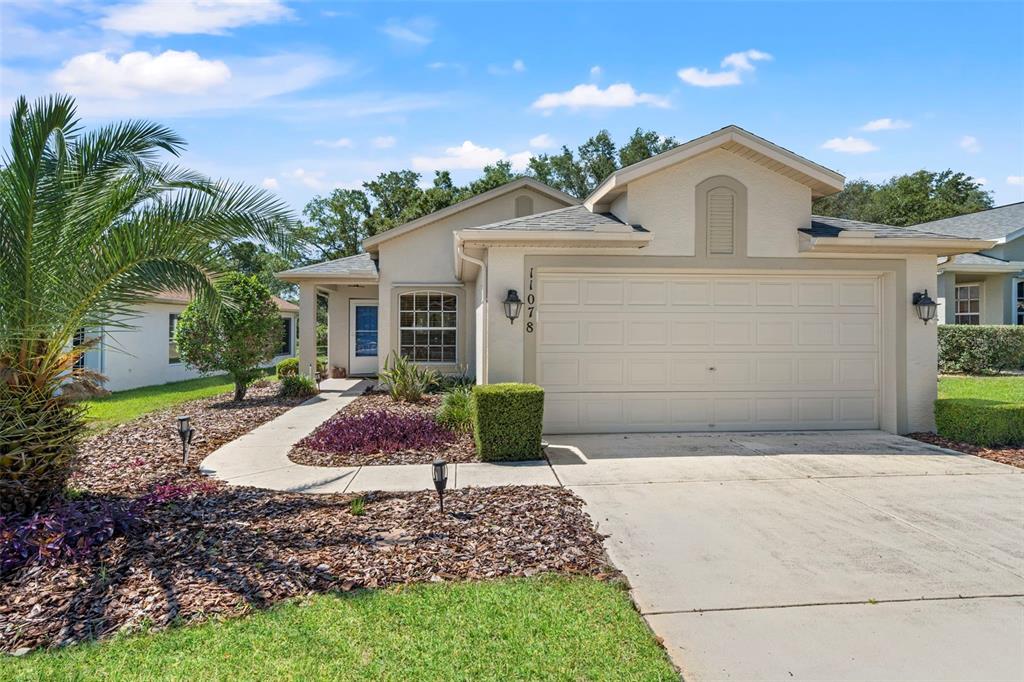 A single-story house with a beige stucco exterior, a two-car garage, and a palm tree — 11078 HEATHROW, SPRING HILL, FL