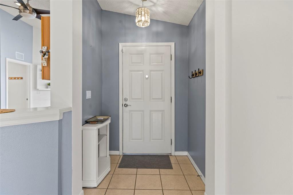 An entryway features a white front door, light blue walls, and beige tile flooring — 11078 HEATHROW, SPRING HILL, FL