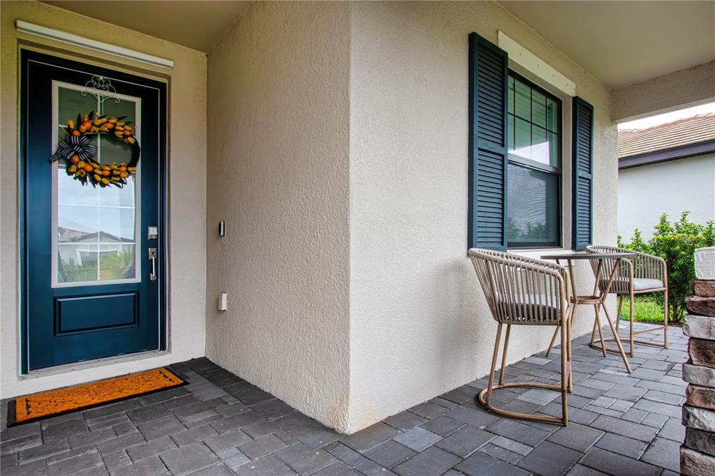 A front porch features a dark blue door, a window with shutters, and two chairs — 5160 CORAL REEF WAY, BRADENTON, FL