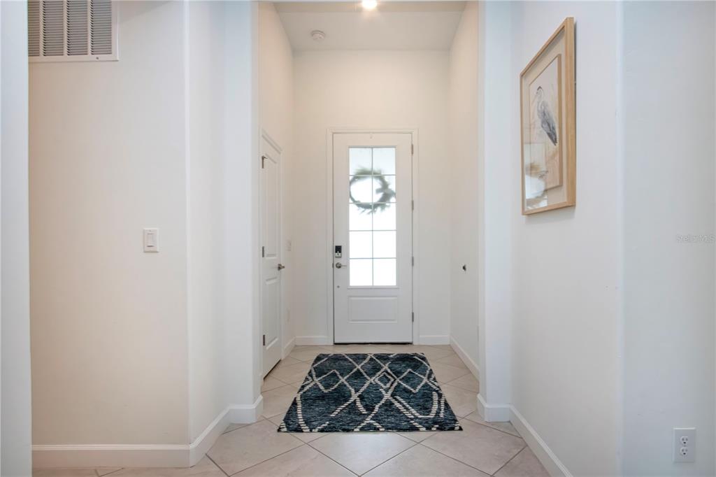 A bright entryway features white walls, tile flooring, a patterned rug, and a front door — 5160 CORAL REEF WAY, BRADENTON, FL