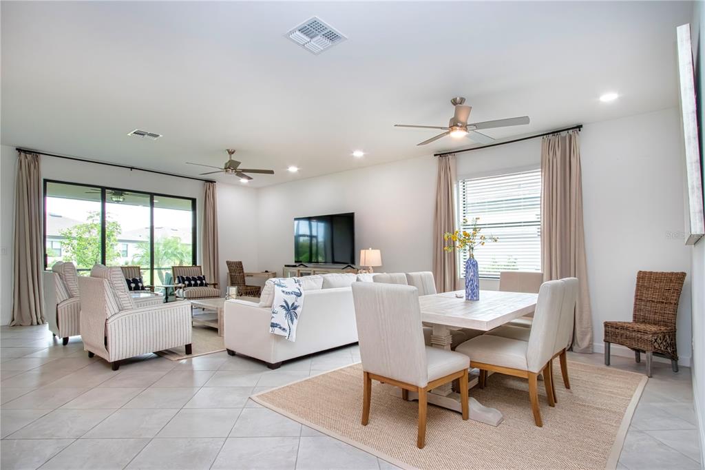 An open-concept living and dining area features tile floors, neutral furniture, and large sliding doors — 5160 CORAL REEF WAY, BRADENTON, FL