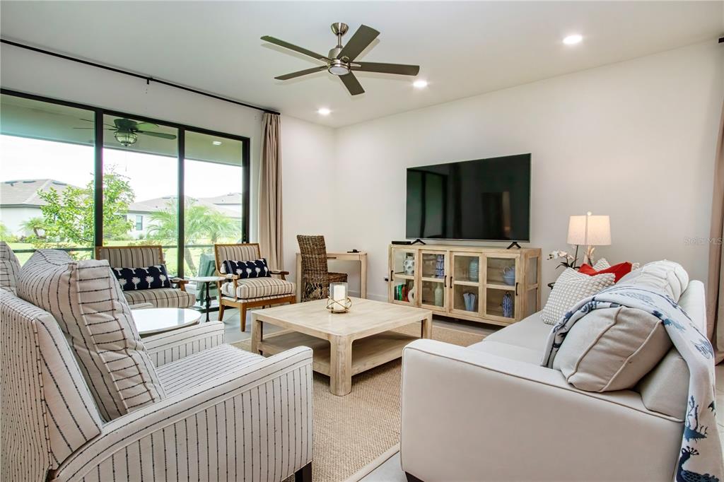 A living room features a large television, a wooden coffee table, and sliding glass doors — 5160 CORAL REEF WAY, BRADENTON, FL