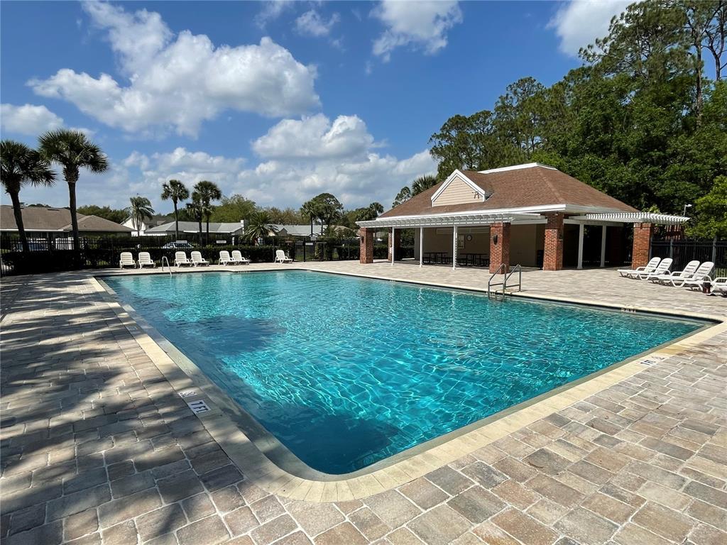 A rectangular swimming pool with a paved deck and a covered clubhouse building — 4228 BOCA WOODS DRIVE, ORLANDO, FL