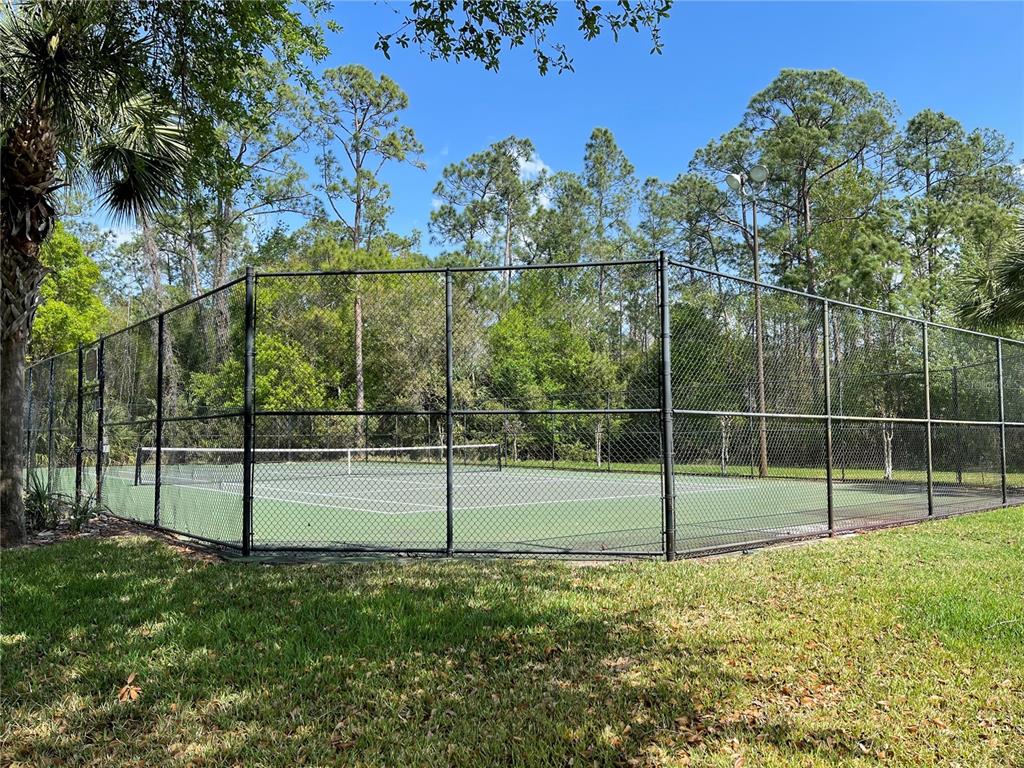 A fenced-in outdoor tennis court surrounded by trees and grass — 4228 BOCA WOODS DRIVE, ORLANDO, FL