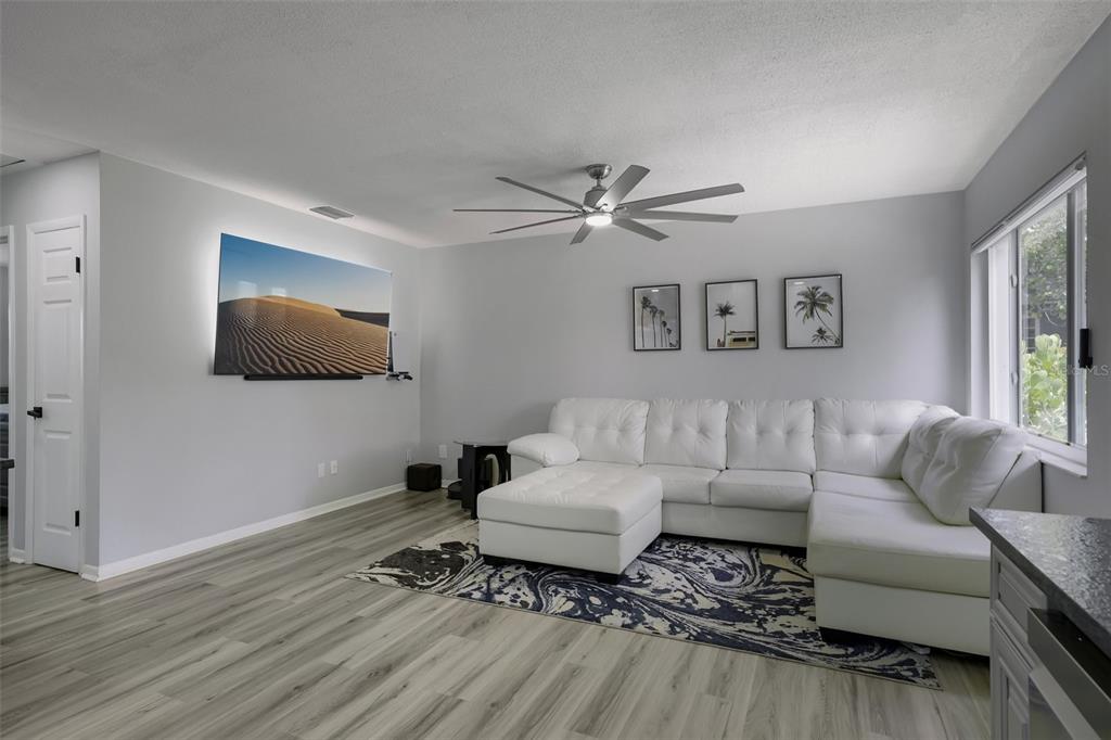A living room features a white sectional sofa, a patterned rug, and a wall-mounted television — 5043 14TH AVENUE N, ST PETERSBURG, FL