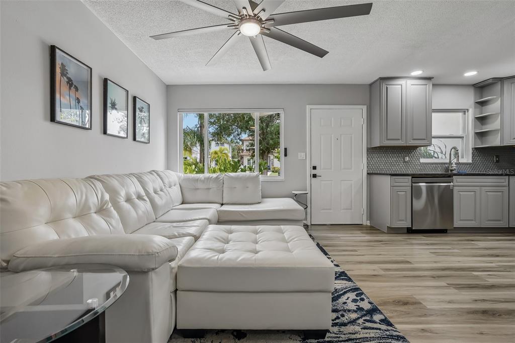 A living room features a white sectional sofa, gray kitchen cabinetry, and light wood flooring — 5043 14TH AVENUE N, ST PETERSBURG, FL