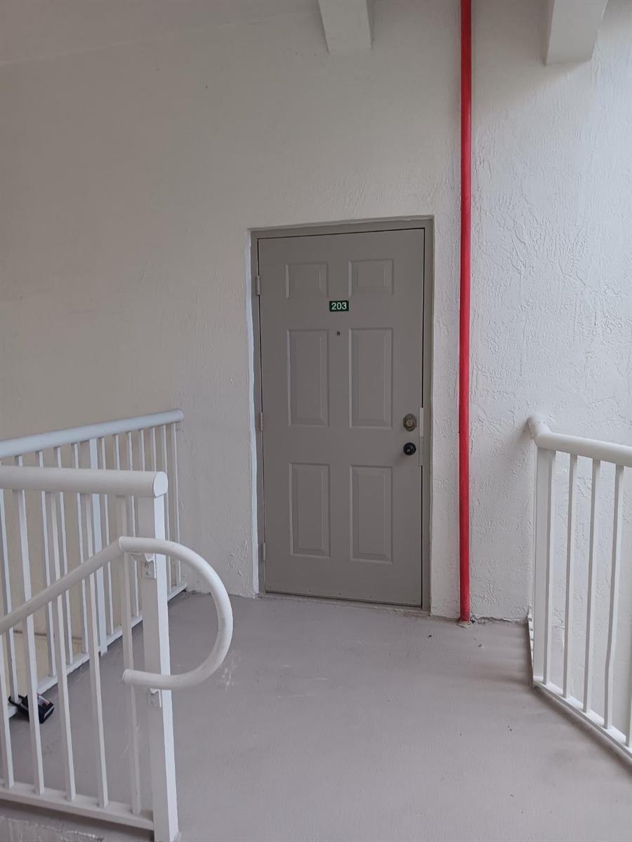 A gray apartment door labeled 203 is situated at the top of a stairwell — 4321 SW 160th Avenue # 203, Miramar FL 33027, MIRAMAR, FL