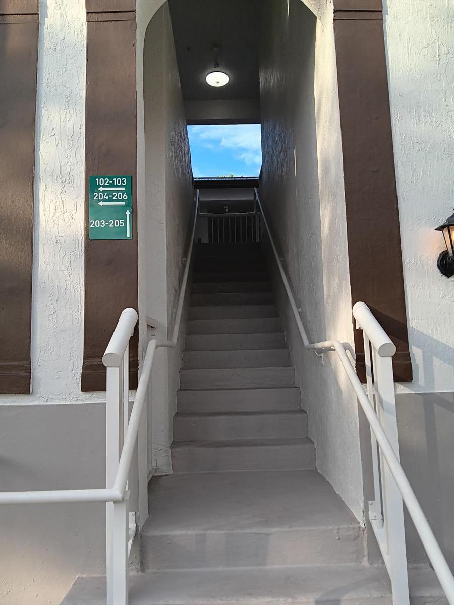 An outdoor concrete staircase leads up to a building entrance with directional signage for apartments — 4321 SW 160th Avenue # 203, Miramar FL 33027, MIRAMAR, FL