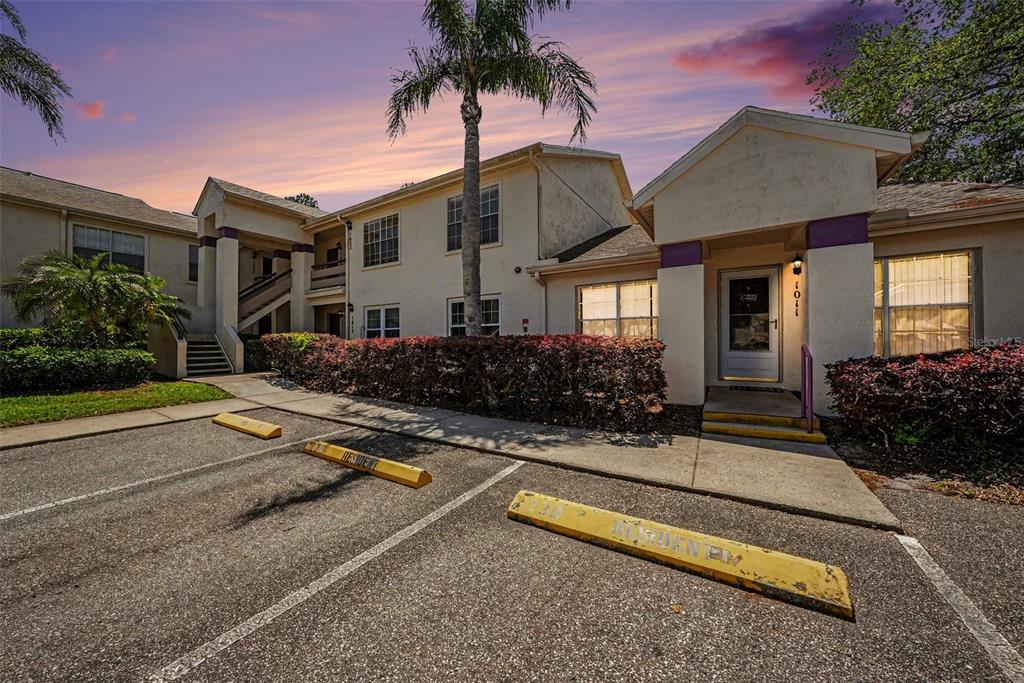 A two-story apartment building exterior features a parking lot with yellow wheel stops — 7816 HARDWICK DRIVE UNIT 1011, NEW PORT RICHEY, FL