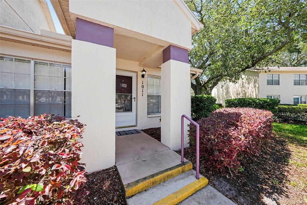 The exterior of a residential building features a covered entryway with steps and purple accents — 7816 HARDWICK DRIVE UNIT 1011, NEW PORT RICHEY, FL