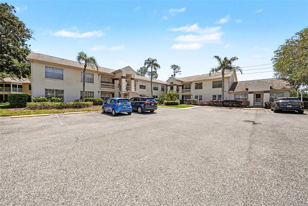 A two-story apartment building exterior with a paved parking lot in the foreground — 7816 HARDWICK DRIVE UNIT 1011, NEW PORT RICHEY, FL