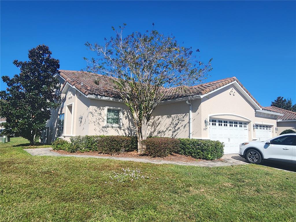 A single-story house with a tiled roof, beige stucco walls, and a two-car garage — 2852 EASTHAM LANE, KISSIMMEE, FL