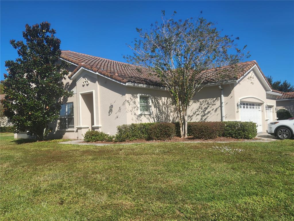 A single-story stucco house with a tile roof, a garage, and a large front tree — 2852 EASTHAM LANE, KISSIMMEE, FL