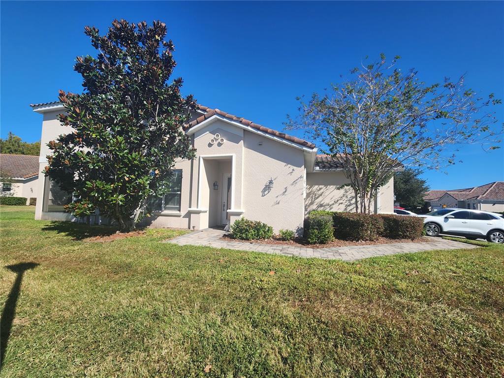 A single-story house with a beige stucco exterior, a tiled roof, and a paved walkway — 2852 EASTHAM LANE, KISSIMMEE, FL