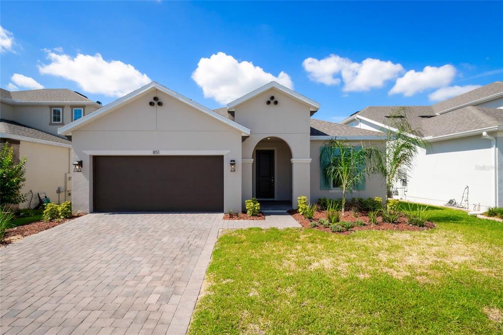 A single-story house with a paved driveway, a two-car garage, and a covered entryway — 851 VINEYARD RIDGE ROAD NW, MINNEOLA, FL