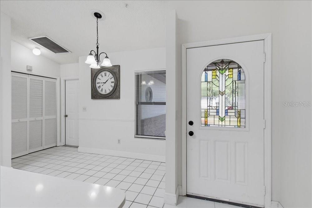 A white-tiled entryway features a front door with stained glass and a wall-mounted clock — 5513 CAURUS COURT, ORLANDO, FL