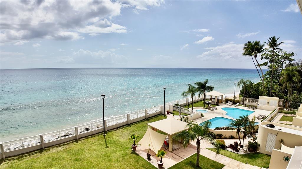 An elevated view of a coastal property featuring a lawn, swimming pools, and oceanfront access — 429 C. PORTO VECCHIO UNIT 401, RINCON, PR