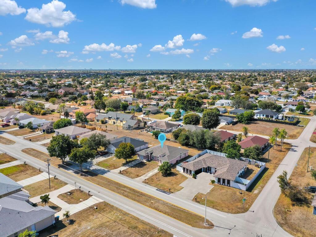 An aerial view of a residential neighborhood featuring a pink house with a blue marker — 1208/1210 SE 24TH AVENUE, CAPE CORAL, FL