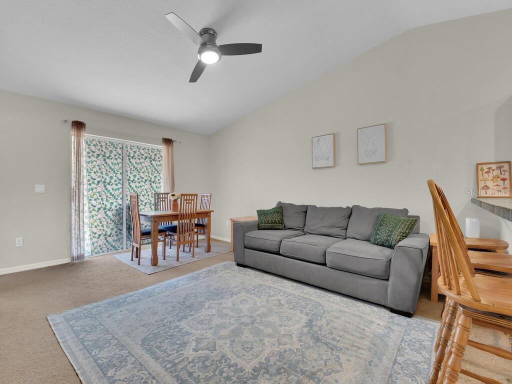 A living room features a gray sofa, a patterned area rug, and a dining set — 1208/1210 SE 24TH AVENUE, CAPE CORAL, FL