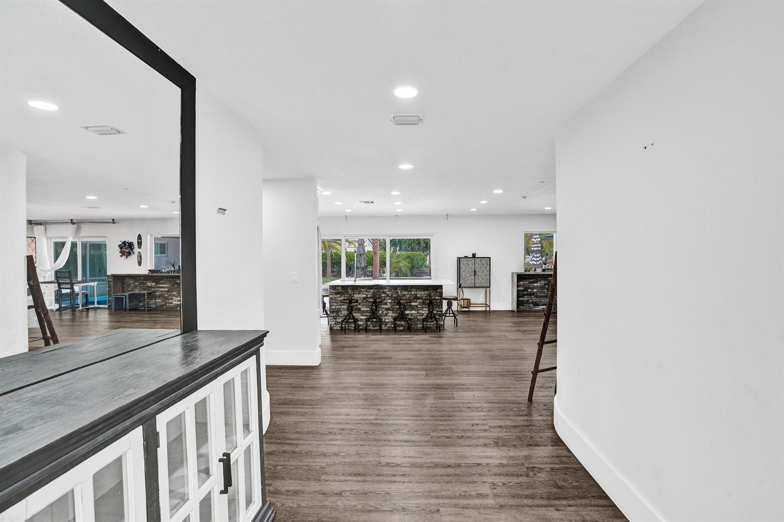 An open-concept living space features wood-look flooring, a kitchen island with bar seating, and recessed lighting — 343 Layne Boulevard, Hallandale Beach FL 33009, HALLANDALE BEACH, FL