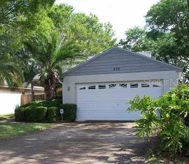 The exterior of a house features a white garage with a gray gabled roof — 650 BELLINGHAM PLACE, PALM HARBOR, FL