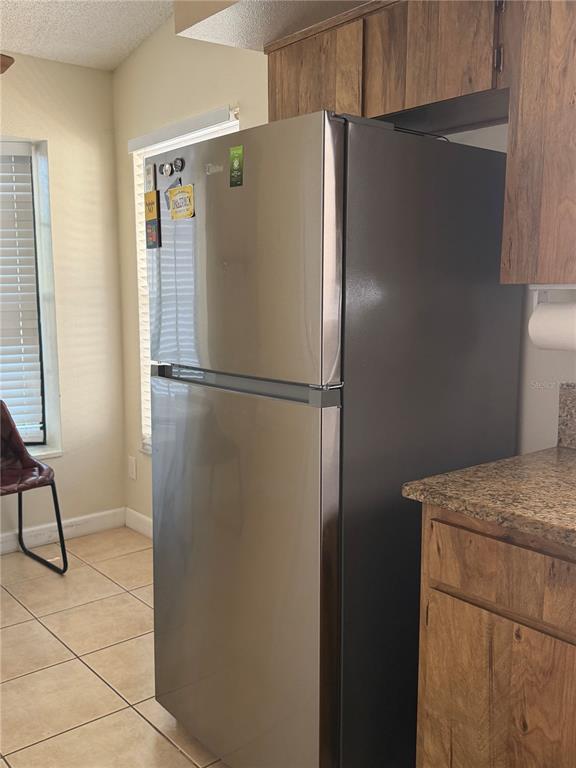 A stainless steel refrigerator stands in a kitchen with wood cabinets and tile flooring — 650 BELLINGHAM PLACE, PALM HARBOR, FL