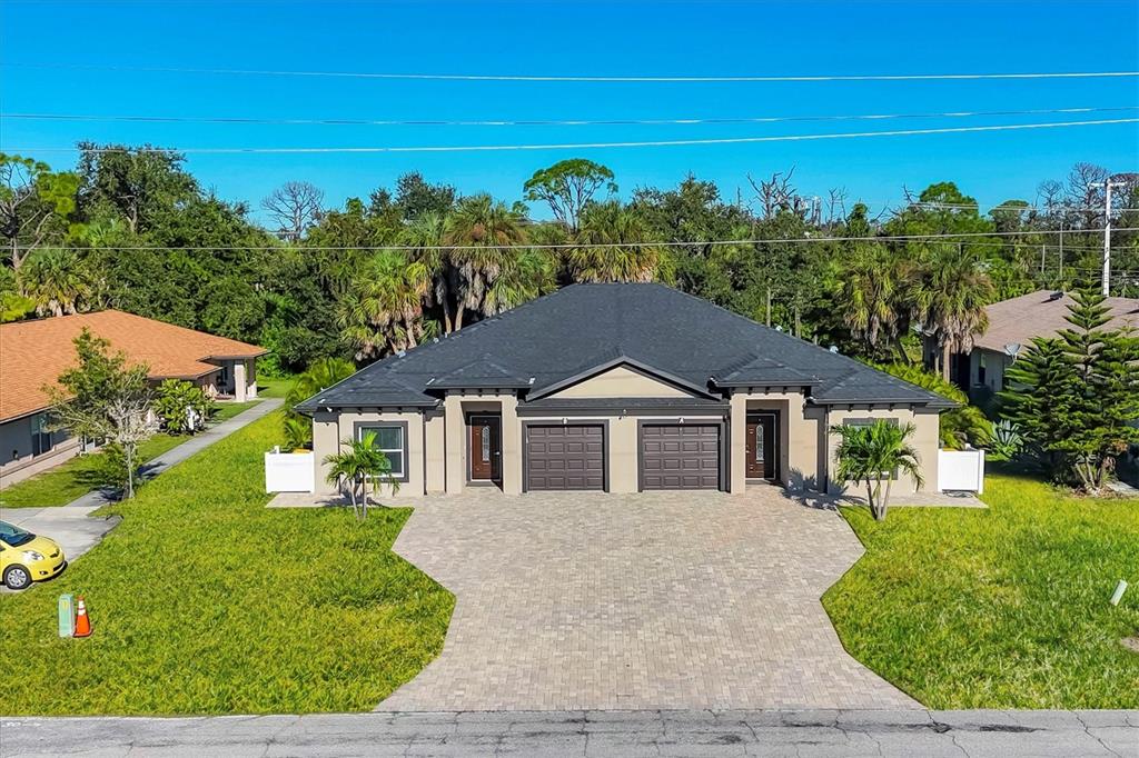 An aerial view of a single-story duplex with a shared paved driveway and dark roofs — 357 BOUNDARY BOULEVARD, ROTONDA WEST, FL